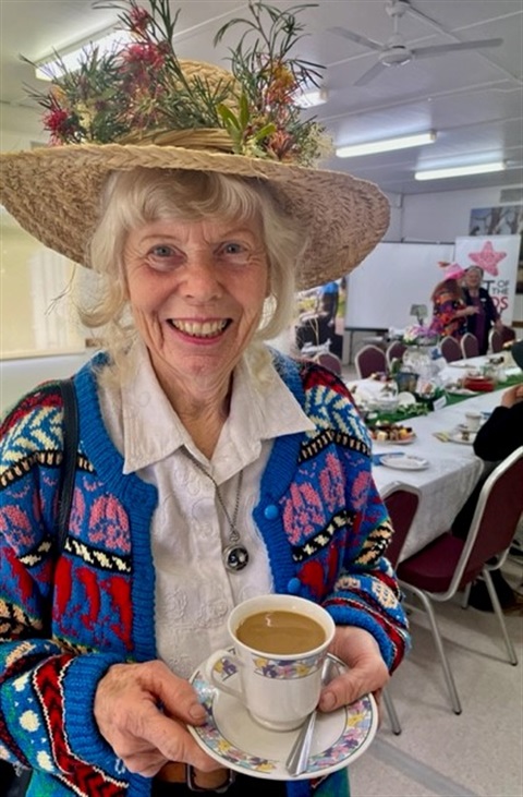 Over 55 woman in a flower hat holding a cup of tea