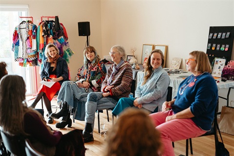 A group of people sitting in a colourful room chatting about art