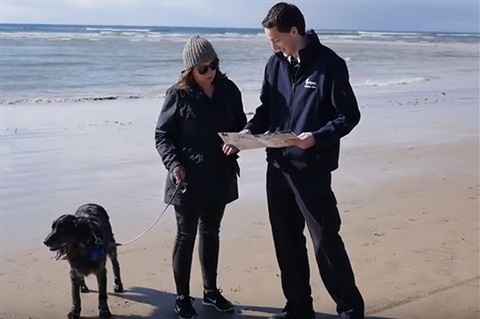 Ranger with woman and dog on beach