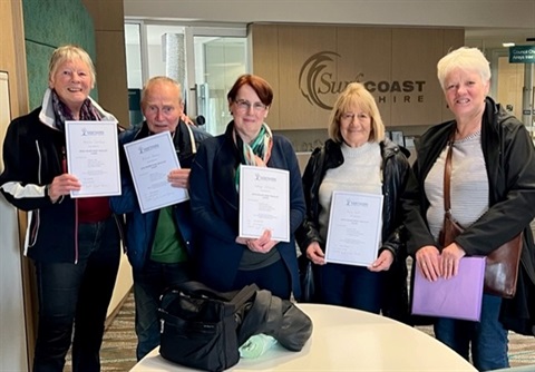 Five older people standing with certificates